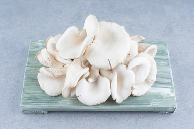 Close up photo of oyster mushroom on wooden board. 