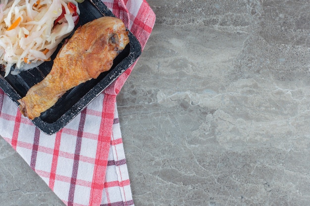 Close up photo.pf pile of sauerkraut and chicken leg on wooden plate.