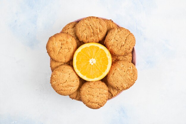 ハーフカットオレンジとクッキーの山の写真をクローズアップ。