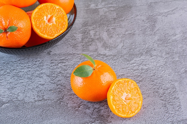 Close up photo of pile of organic tangerines on grey.