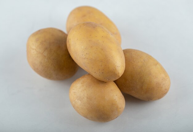 Close up photo of pile of potatoes on white background.