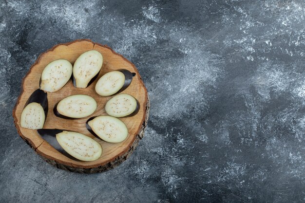 Close up photo of Pile of sliced aubergine on wooden board.