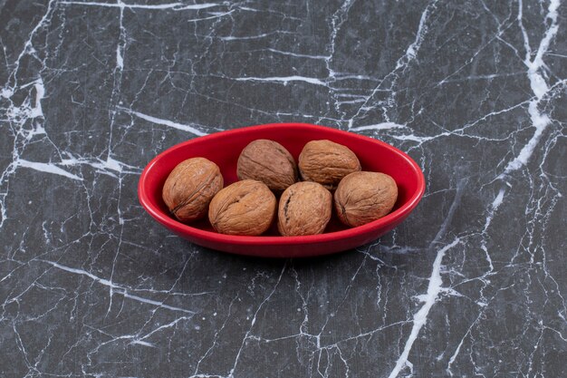 Close up photo pile of walnut in red bowl