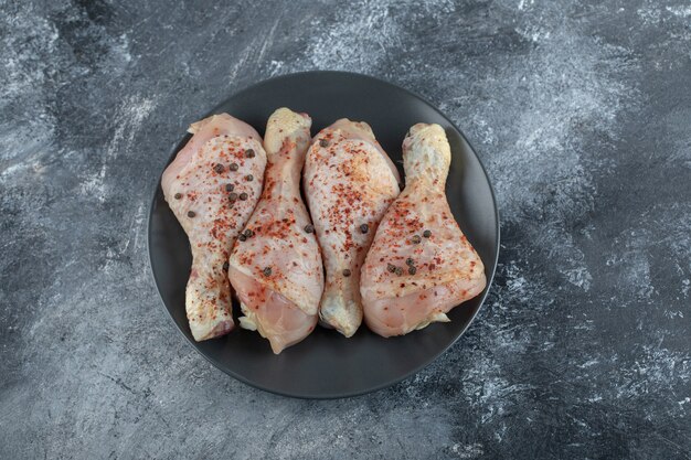 Close up photo of raw marinated chicken legs on grey background.