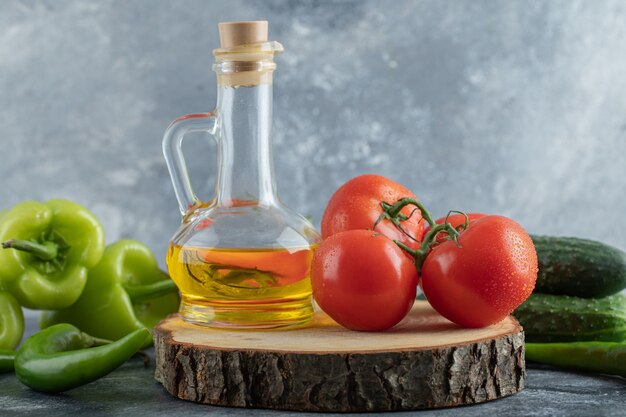 Close up photo of red tomato with green peppers and bottle of oil