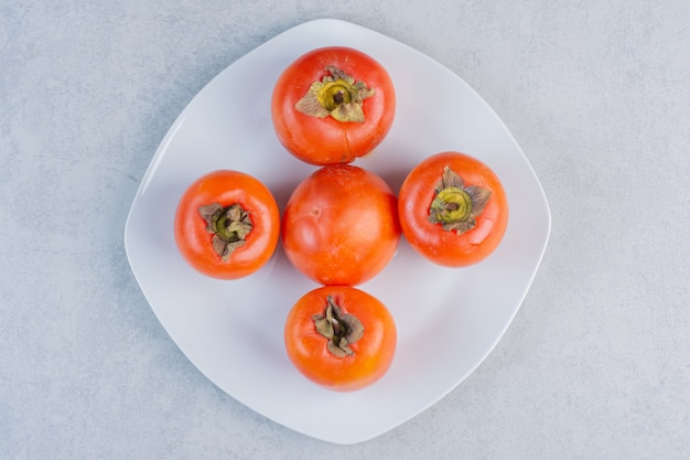 Close up photo of Ripe orange persimmon fruit . Fresh persimmon on white plate . 