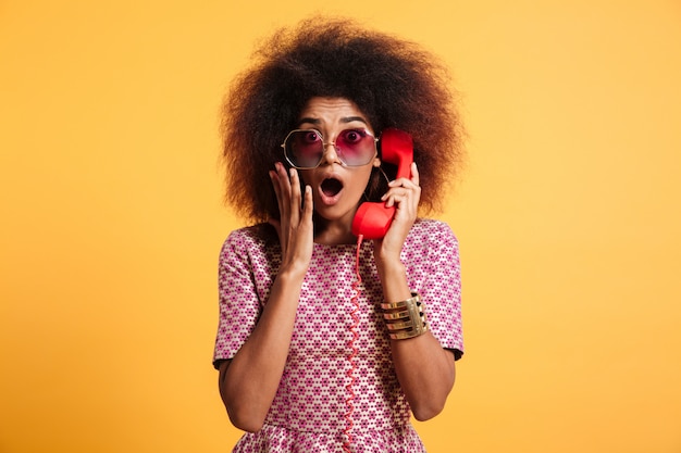 Close-up photo of shocked retro girl with afro hairstyle holding retro phone