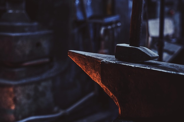 Close up photo shoot of hammer and anvil at dark smith workshop.