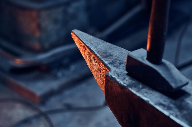 Close up photo shoot of hammer and anvil at dark smith workshop.