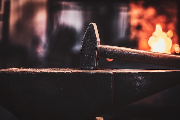 Free photo close up photo shoot of hammer and anvil at dark smith workshop.