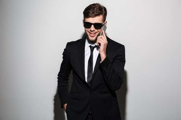 Close-up photo of smiling handsome businessman in glasses talking on mobile phone,