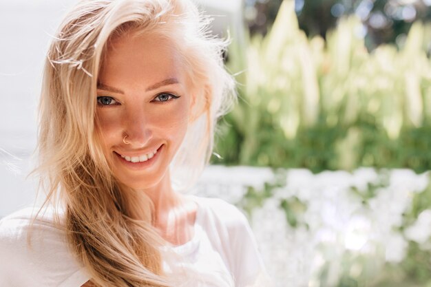 Close-up photo of smiling woman with pierced nose. Portrait of romantic blonde lady smiling