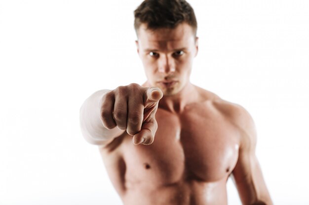 Close-up photo of strong sports man with short haircut pointing with finger on you, selective focus on finger