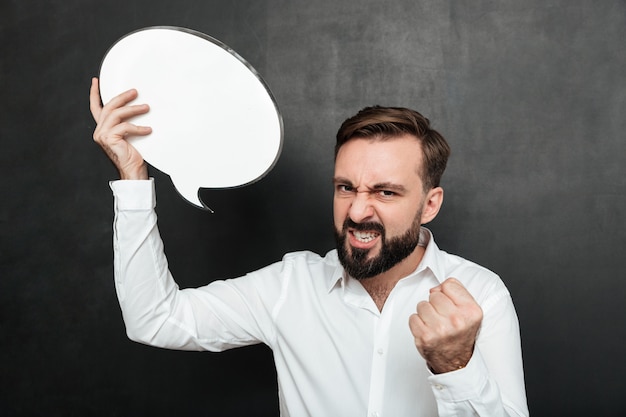 Close up photo of successful man holding blank speech bubble encouraging to be self-motivated and ambitious over dark gray wall copy space