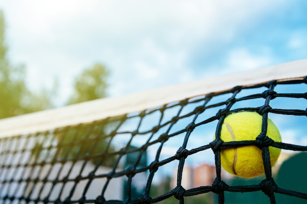 テニスボールがネットにぶつかるクローズアップの写真。スポーツコンセプト。