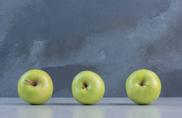 Close up photo of three green fresh apples. 