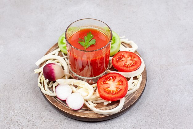 Close up photo of tomato slices with radish and cabbage with sauce on wooden board.