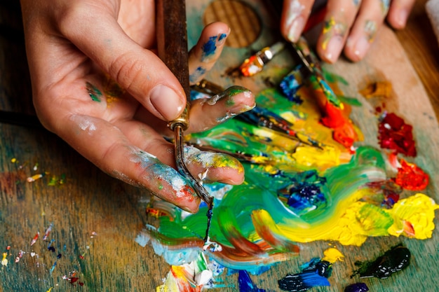 Free photo close up photo of woman mixing oil paints on palette