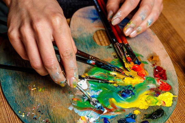 Close up photo of woman mixing oil paints on palette