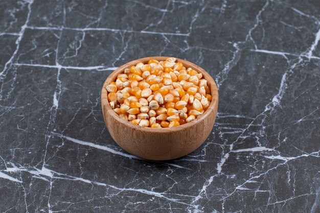 Close up photo of wooden bowl full with corn seeds.