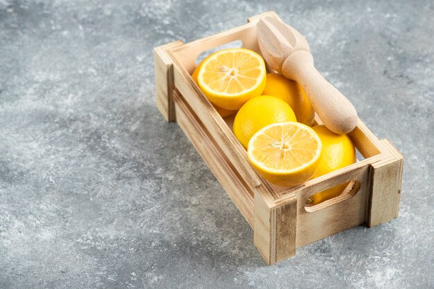 Close up photo of wooden box full with fresh lemons.