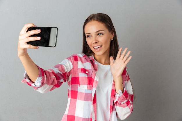 Foto del primo piano di giovane bella donna, prendendo la foto del selfie dai suoi telefoni