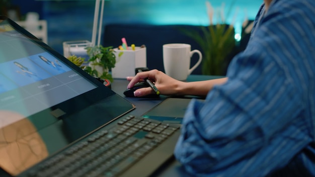 Close up of photographer hands using graphic tablet and stylus while retouching pictures in photography studio. Artist doing retouch work with editing software on computer and equipment