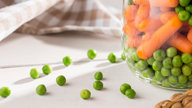 Close-up of pickled peas and baby carrots in jars