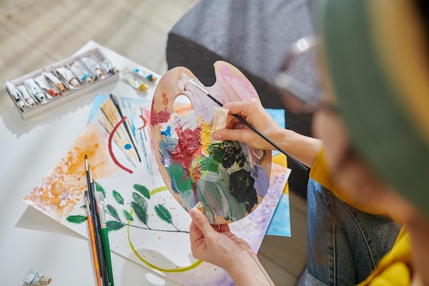 Close up picture of an artist mixing the paints on a palette