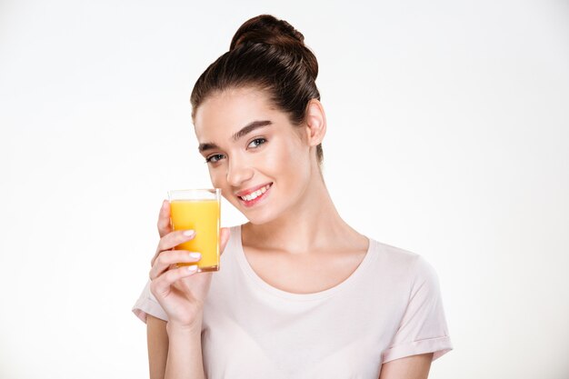 Close up picture of glad gorgeous woman drinking sweet orange juice from transparent glass with smile