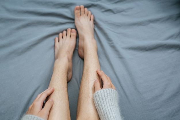 Free photo close up picture of hands touching leg softly on bed