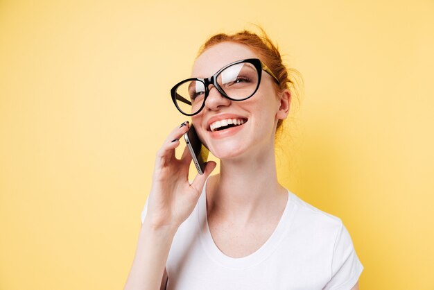Close up picture of happy ginger woman talking by smartphone