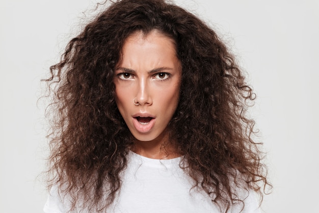 Close up picture of serious curly woman with open mouth