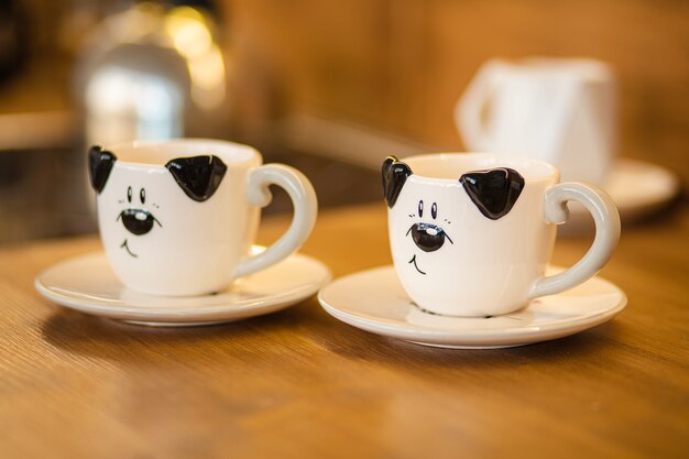 Free photo close-up picture of two black and white cups with dog picture on they is on the brown table