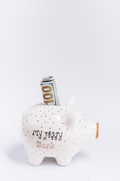 Free Photo close-up of piggybank with hundred banknote on white backdrop