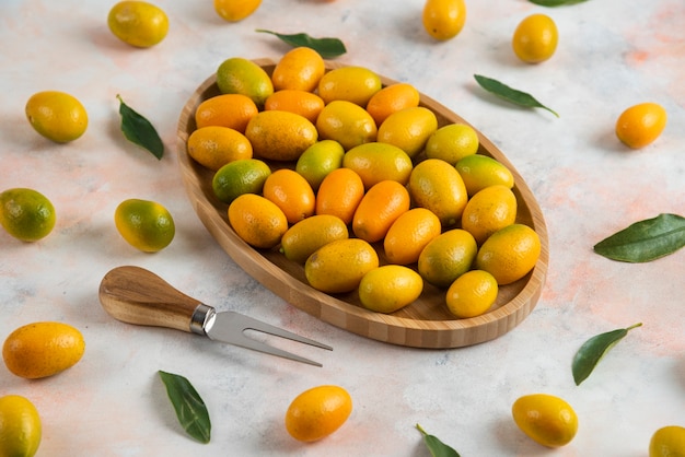 Close up of pile of kumquats on wooden plate