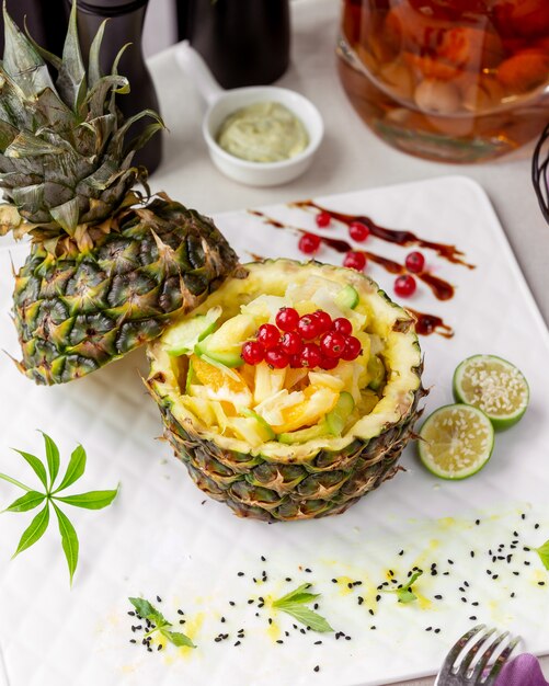 Free photo close up of pineapple bowl with orange cucumber red currant and pineapple