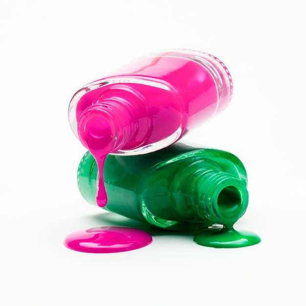 병에서 떨어지는 분홍색과 녹색 매니큐어의 클로즈업