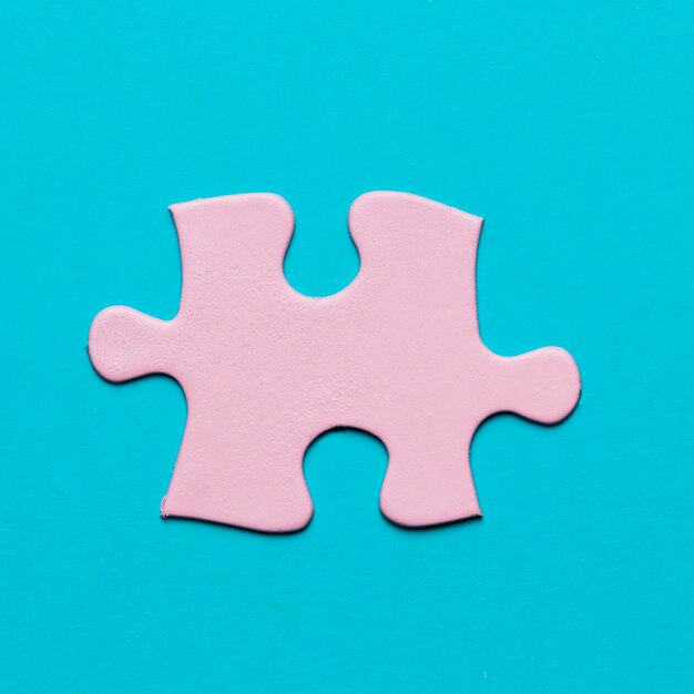Close-up of pink jigsaw puzzle piece on blue background