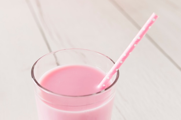 Крупный розовый молочный коктейль в стакане с соломой