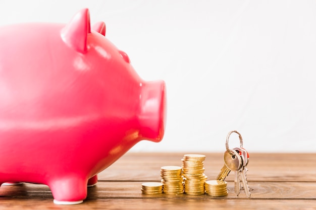 Free photo close-up of pink piggybank near stacked coins and key