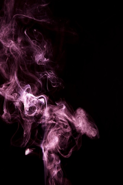 Close-up of pink smoke spread around black background