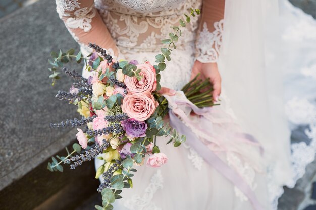 花嫁の手でピンクと紫のウェディングブーケのクローズアップ