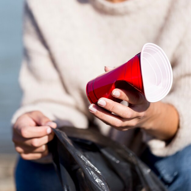 海辺でのクローズアップのプラスチックカップ