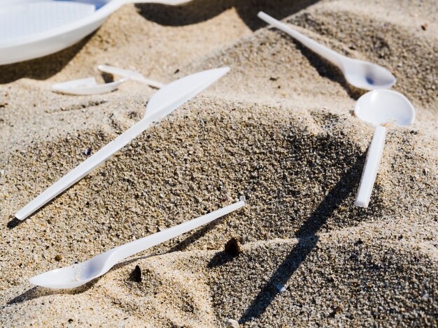 ビーチで砂の上のプラスチック製カトラリーのクローズアップ