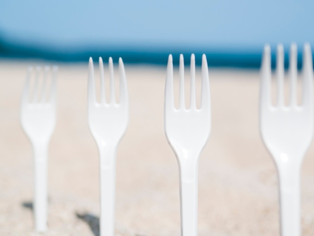 Close-up of plastic forks stuck in sand on the beach