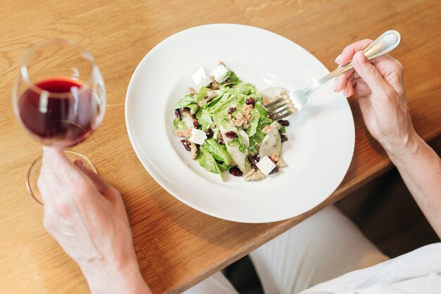 Close-up plate with salad and wine on wooden table