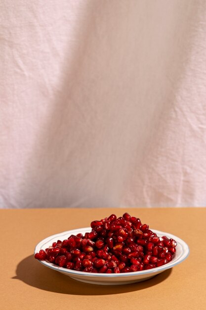 Close-up of pomegranate seeds on plate over brown desk against white curtain