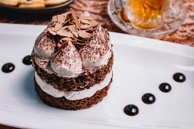 Close up of portioned layered cacao cake with white cream and chocolate pieces