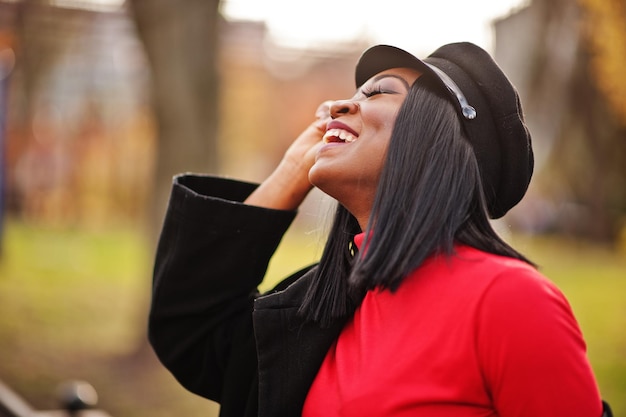 Close up portrait of african american fashion girl in coat and newsboy cap posed at street